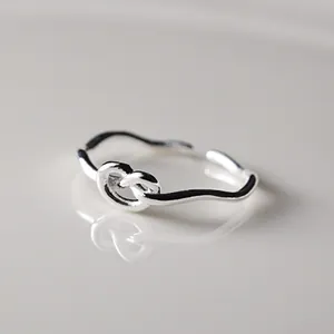 Close-up of minimalist sterling silver knot ring with adjustable open band design
