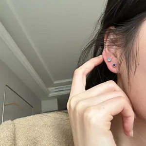 Detailed close-up showing mini heart-shaped zircon stud earrings on an Asian model's ear