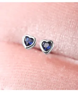 Close-up detail of 925 sterling silver heart earrings with blue cubic zirconia stones