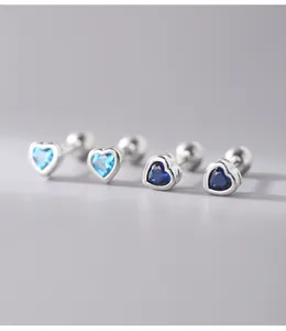Macro detail of heart-shaped silver stud earrings with blue zircons and screw backs