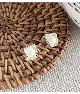 Detail of 925 silver irregular square stud earrings featuring a central pearl inlay.