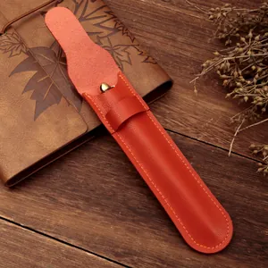 Astuccio minimalista per penne in pelle PU arancione su un taccuino vintage