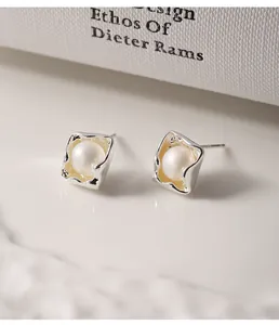 Detailed close-up of 925 silver irregular square stud earrings with pearl centers.