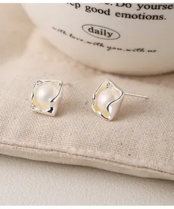 Close-up detail of irregular 925 silver square stud earrings with pearl inlay