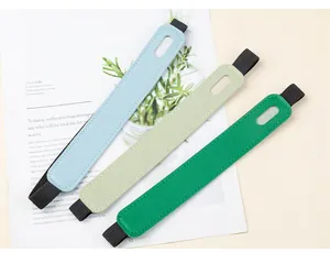 Close-up view of three colorful PU leather pen sleeves with elastic bands on a magazine