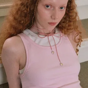 Detailed close-up view of pink bow cord necklace with silver heart pendants on model