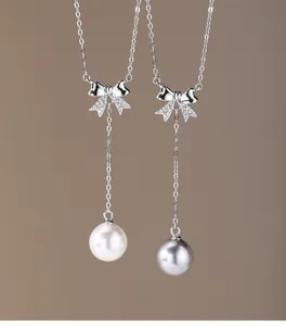 Detailed view of 925 silver bow necklaces with white and grey pearl pendants.