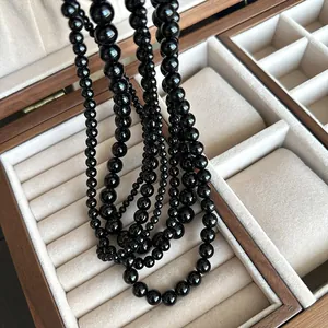 Close-up of elegant black onyx bead necklaces draped in a premium wooden jewelry box