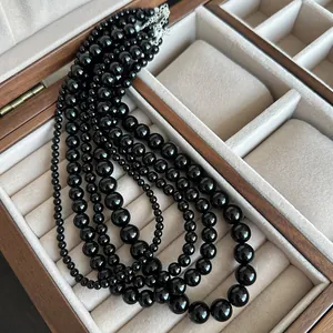 Close-up of multi-layered black agate bead necklace in a luxury wooden jewelry box