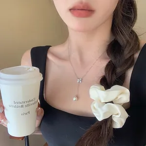 Close-up of elegant 925 silver bow necklace with pearl drop on a female model