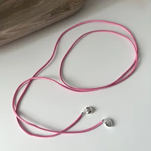 Detail of pink suede cord necklace featuring silver heart charms for multi-style wear