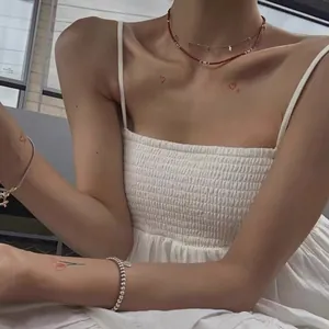 Dettaglio di collane a strati in argento S925 e perline rosse indossate su una modella