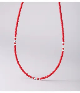 Dettaglio macro di una collana girocollo di perline rosse con inserti in argento S925