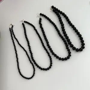 Detailed view of four black onyx beaded necklaces with varying bead sizes and silver clasps