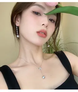 Close-up of elegant sterling silver bow necklace and pearl earrings on model
