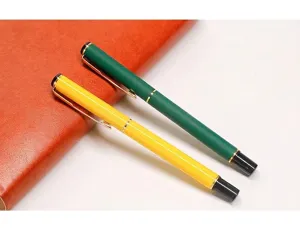 Détail de stylos gel en métal vert et jaune sur un carnet de notes en cuir