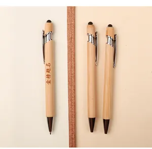 Three eco-friendly bamboo ballpoint pens with capacitive stylus tips on textured paper