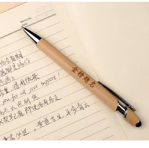 Close-up of a natural bamboo ballpoint pen with stylus tip on a lined notebook