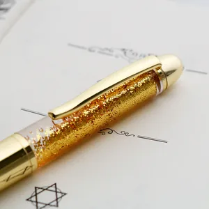 Macro view of a luxury gold ballpoint pen barrel filled with sparkling golden sequins