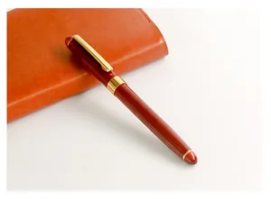 Professional detail view of a vintage redwood rollerball pen resting on a leather journal