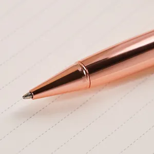 Close-up of elegant rose gold metal ballpoint pen on lined paper, minimalist design.