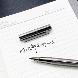 Professional textured silver metal rollerball pen writing on a lined notebook page