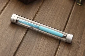 Close-up of a transparent cylindrical pen box with a blue crystal ballpoint pen