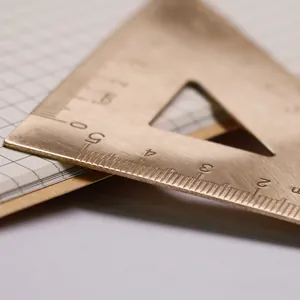 Regla triangular de latón vintage con escala grabada con láser sobre un cuaderno