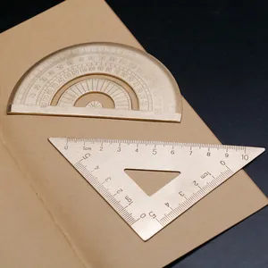 Juego de geometría de latón vintage con transportador y escuadra sobre un cuaderno