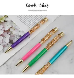 Close-up of elegant crystal ballpoint pens with decorative gold foil flakes inside