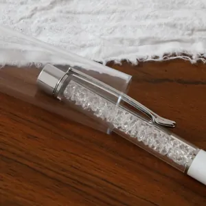 Elegant white ballpoint pen filled with sparkling crystals in clear cylindrical plastic gift box