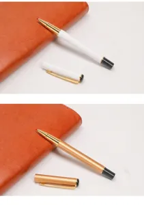 Détail de stylos signature en métal blanc et or rose avec un carnet en cuir marron