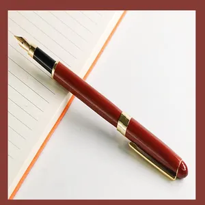 Detailed view of redwood fountain pen with gold accents on a notebook