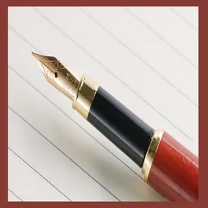 Detailed macro view of a high-quality gold-plated fountain pen nib on white lined paper