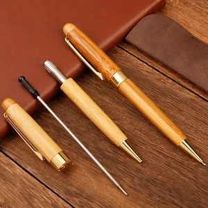 Set de bolígrafos de bambú natural con detalles dorados sobre madera