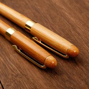 Elegantes bolígrafos de bambú natural con detalles dorados sobre madera rústica.