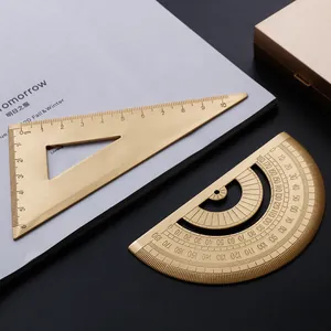 Professional vintage brass ruler set with protractor and triangle for creative drafting desk.