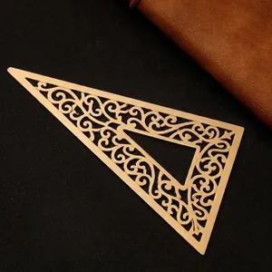 Vintage minimalist brass triangular ruler displayed on a dark textured background