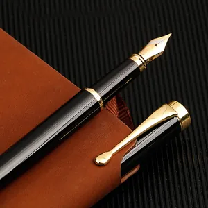Elegant black and gold business metal fountain pen placed on a brown leather notebook