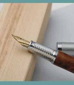 Macro detail of a gold fude nib on a sandalwood fountain pen with textured metal grip.
