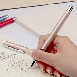 Elegant champagne gold metal rollerball pen held in hand writing on a cream notebook