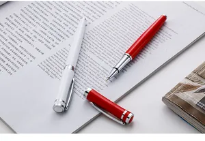 Close-up of red and white metallic business rollerball pens on an open magazine page