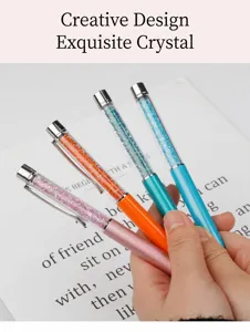 Primo piano dettagliato di quattro penne a sfera colorate riempite di strass di cristallo.