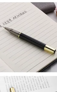 Premium black and gold metal business rollerball pen resting on a classic lined notebook