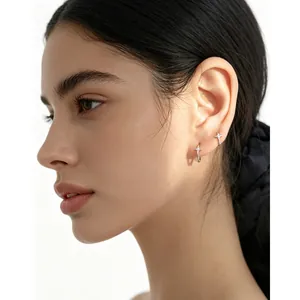 Boucles d'oreilles créoles étoile en argent S925 avec pierres portées par un mannequin.