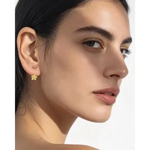 Détail de boucles d'oreilles fleurs en or en argent 925 portées par un mannequin