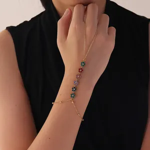 Elegante pulsera anillo dorada con dijes de flores multicolores usada en la mano detalle