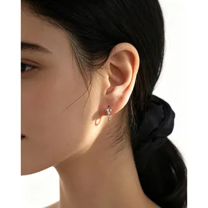 Primer plano de pendientes de aro minimalistas de plata 925 con un diseño de cuentas