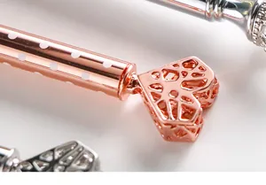 Makroaufnahme eines roségoldenen Kugelschreibers mit filigranem, hohlem Herz-Dekor.