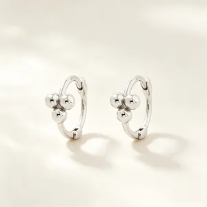 Detalle macro de pendientes de aro de plata 925 con tres perlas decorativas pulidas